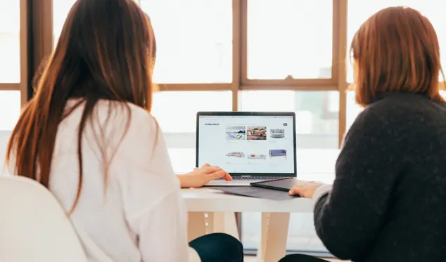 Two colleagues reviewing a website on a laptop
